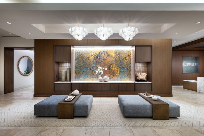 Luxurious apartment lobby with elegant chandeliers, modern seating, and a stunning abstract wall art centerpiece at Hanover Post Oak.