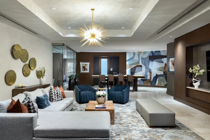 Elegant living room featuring a modern chandelier, stylish gray sectional sofa, and artistic decor with a vibrant abstract mural.