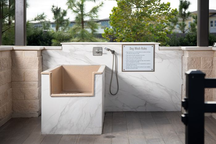 Luxurious marble-finished pet wash station surrounded by nature, featuring a modern faucet and convenient wash area.