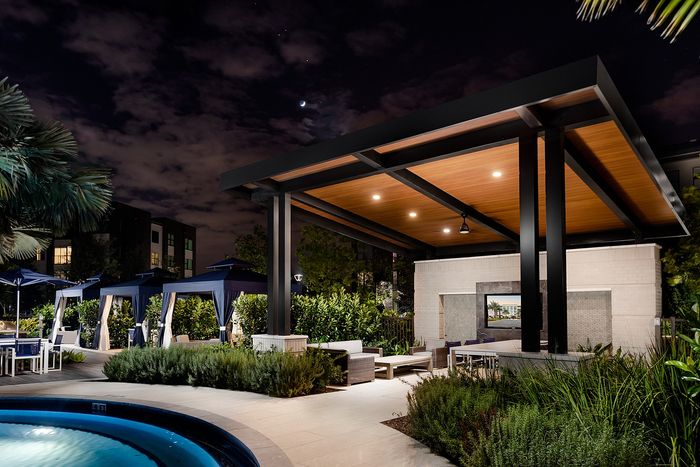 Luxurious outdoor lounge area with modern design, featuring elegant cabanas and lush greenery under a starlit sky.