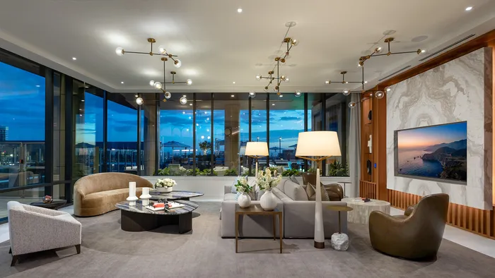 Luxurious open-plan living room with chic decor, modern lighting fixtures, and floor-to-ceiling windows offering a stunning evening view.