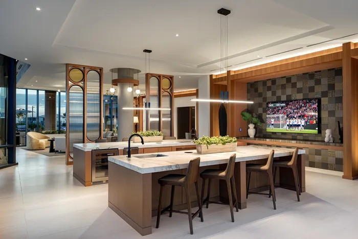 Modern open-concept living space with a sleek kitchen island, stylish seating, and a cozy lounge area featuring a wall-mounted TV.