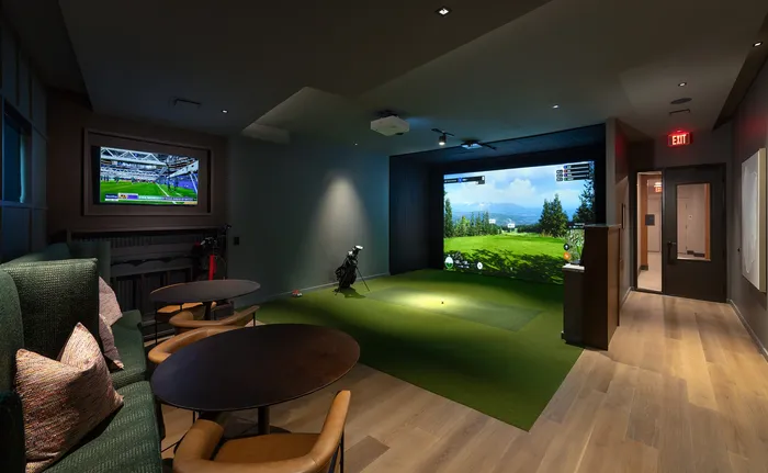 Luxurious entertainment room with a golf simulator and cozy seating area, ideal for relaxation and leisure activities.