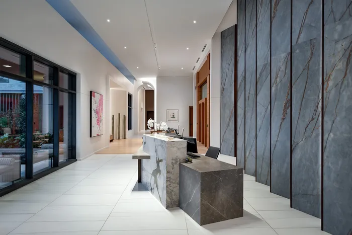 Elegant modern lobby with sleek marble reception desk, high ceilings, and artistic wall design.