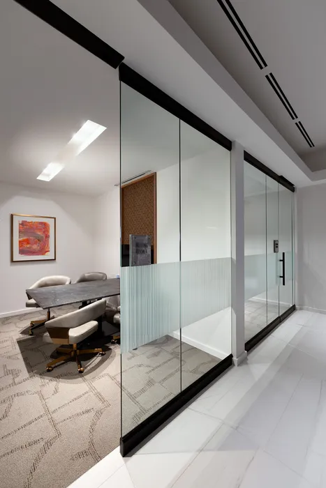 Sleek modern meeting room with glass walls, elegant furnishings, and contemporary artwork.