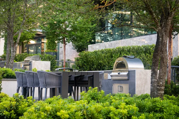 Elegant outdoor space featuring a modern grill station surrounded by lush greenery, ideal for entertaining.