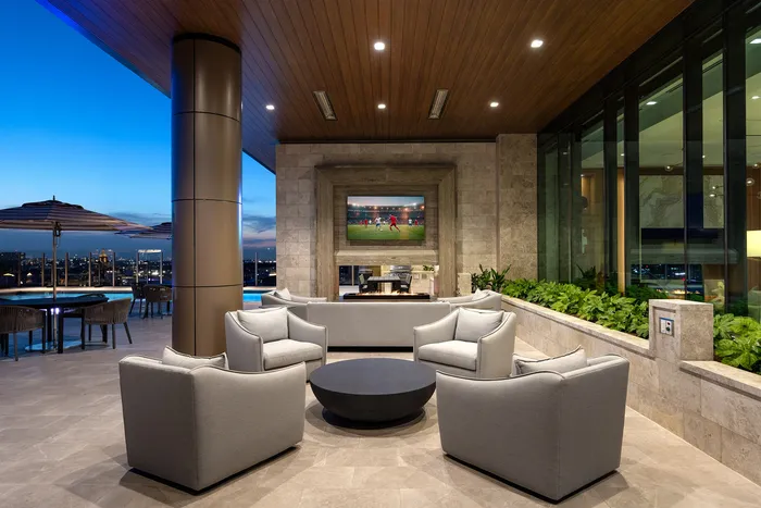 Luxurious open-air lounge with plush seating, modern fireplace, and panoramic city views, perfect for entertaining at sunset.
