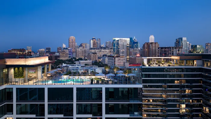 Luxurious urban apartment building with a stunning rooftop pool and night-time cityscape views.
