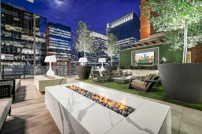 Luxurious rooftop lounge with modern fire pit, stylish seating, and breathtaking city skyline views.