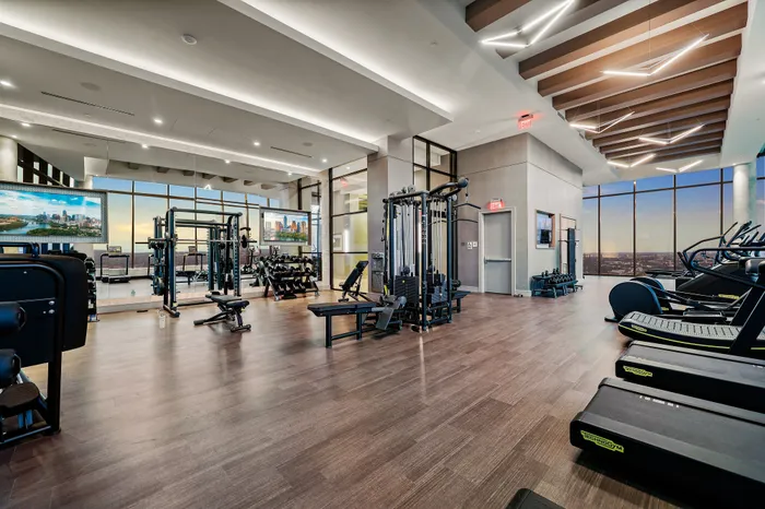 Luxurious apartment gym with state-of-the-art fitness equipment, panoramic city views, and stylish modern design.