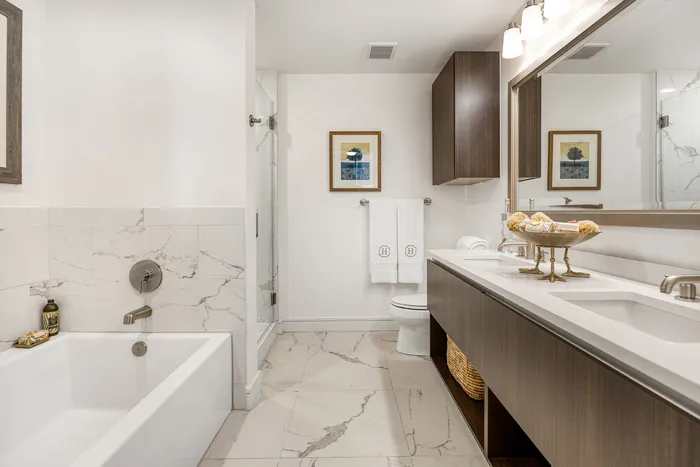 Elegant modern bathroom featuring a luxurious bathtub, chic dual-sink vanity, and sleek marble tile flooring.