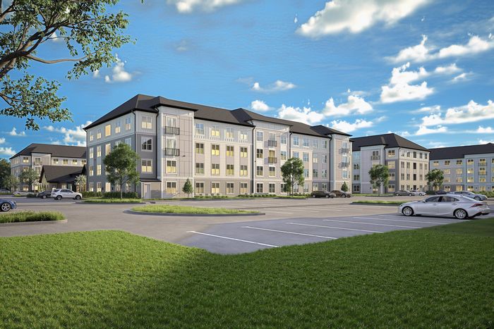 Modern apartment complex with spacious parking, lush greenery, and elegant facade under a vibrant blue sky.
