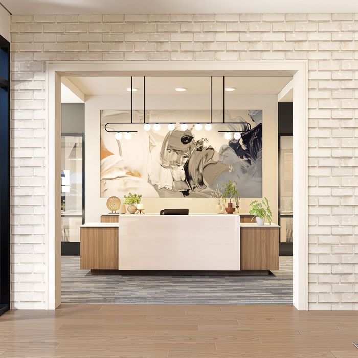 Modern reception area with sleek white desk, vibrant artwork, and stylish lighting in a welcoming space.