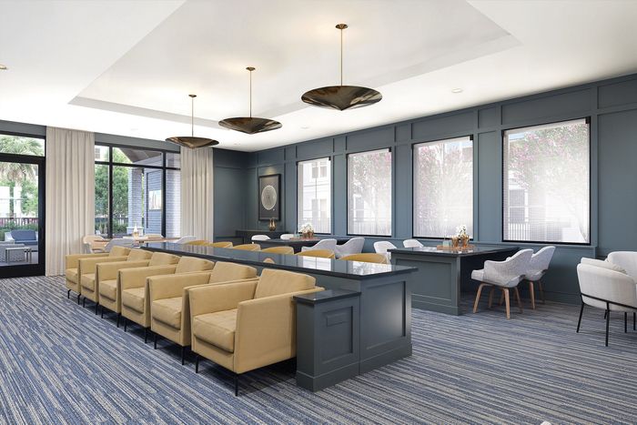 Elegant communal lounge with modern decor featuring plush beige seating, chic pendant lighting, and large windows offering natural light.
