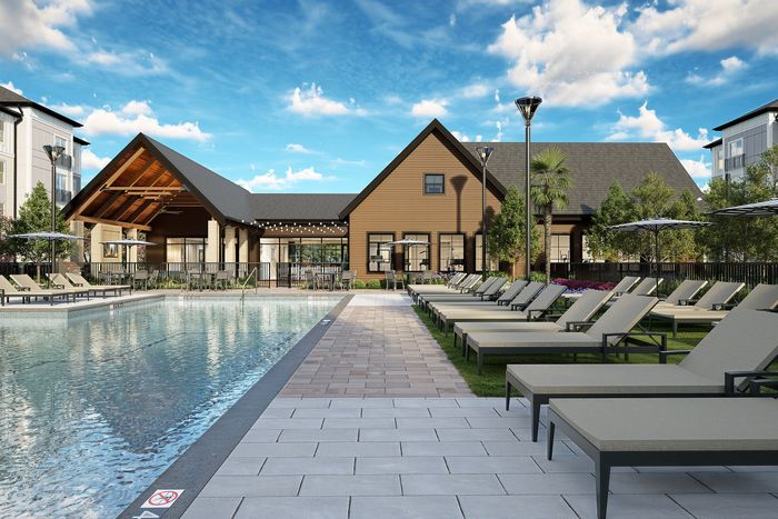 Inviting outdoor pool area with modern lounge chairs and a charming clubhouse, set against a vibrant blue sky.