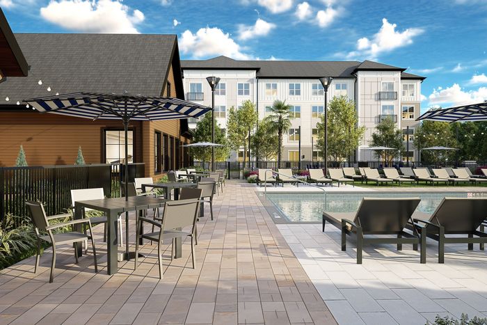Chic outdoor pool area with lounge chairs and shaded seating, set against a stylish apartment complex and lush greenery.