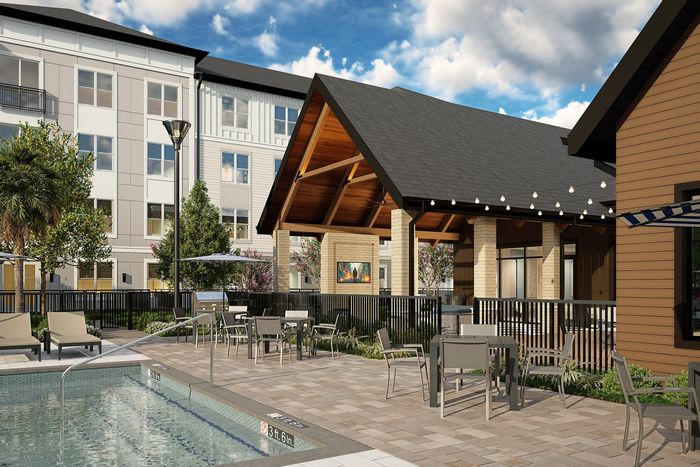 Modern outdoor pool area with stylish lounge chairs and contemporary patio seating, surrounded by elegant apartment architecture and lush greenery.