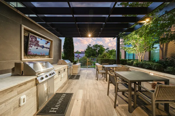 Elegant outdoor kitchen with modern stainless steel grills and dining area, set against a scenic sunset view.