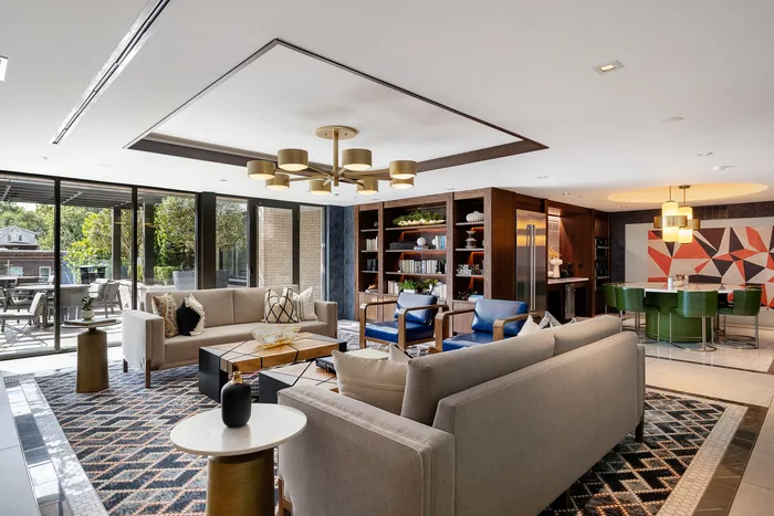 Luxurious living room with modern decor, featuring plush sofas, elegant lighting, and floor-to-ceiling windows opening to a scenic patio.