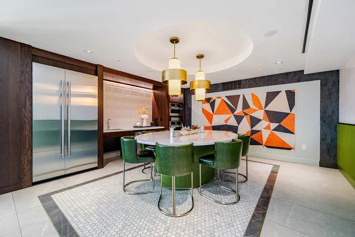 Elegant kitchen with a modern circular dining table, plush green chairs, chic pendant lighting, and geometric wall art.