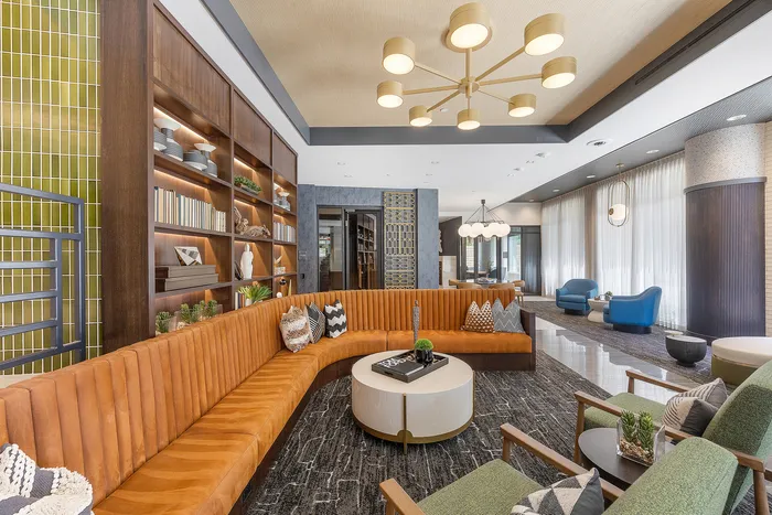 Elegant contemporary lounge with a plush orange sectional sofa, stylish shelving, and modern lighting, creating a cozy ambiance.