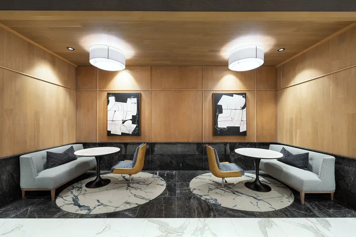 Sophisticated seating area with modern decor, featuring elegant round tables, abstract artwork, and plush sofas on a marble floor.