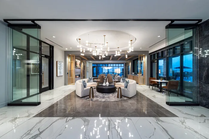 Luxurious modern lounge with elegant furnishings, marble flooring, and a stunning city view.