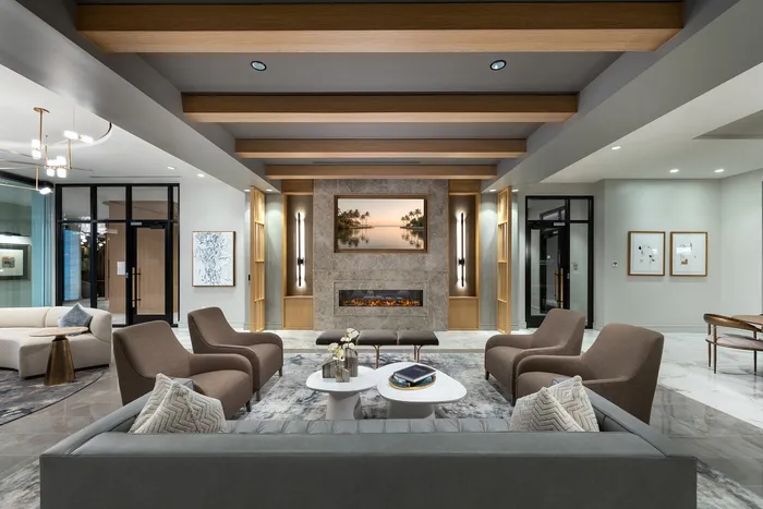 Luxurious apartment lobby with modern gray sofas, stylish armchairs, and a sleek fireplace, exuding elegance and comfort.