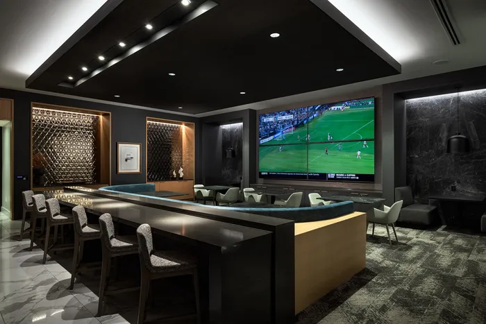 Luxurious modern lounge area with sleek bar seating, ambient lighting, and large screen for entertainment.