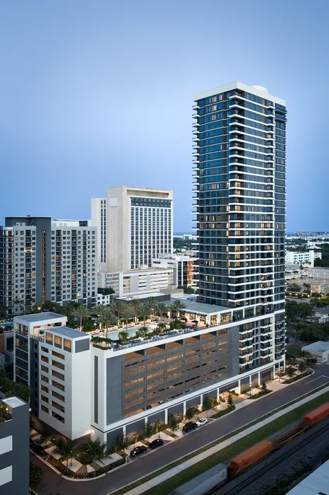 Stunning modern high-rise apartment building with sleek glass facade and rooftop amenities, set against a vibrant cityscape.