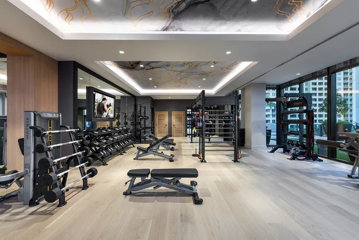 Luxurious fitness center with modern equipment and expansive floor-to-ceiling windows offering a vibrant city view.