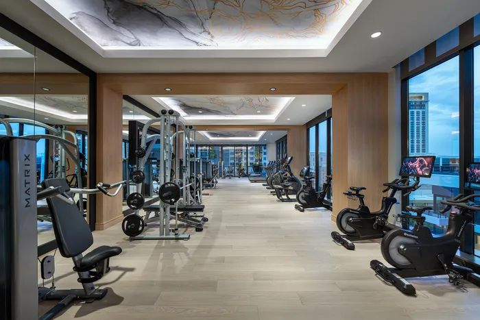 Luxurious fitness center with state-of-the-art gym equipment, sleek wooden flooring, and expansive city views.