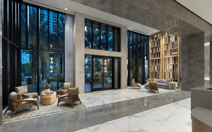 Elegant apartment lobby with modern seating arrangement, large floor-to-ceiling windows, and luxurious marble flooring.