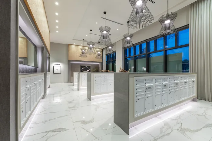 Elegant and modern mailroom with sleek white cabinetry, polished marble floors, and contemporary pendant lighting.
