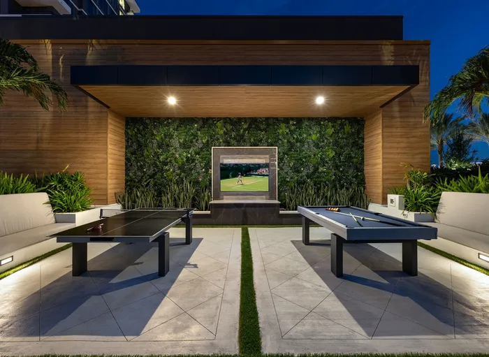 Luxurious outdoor entertainment area featuring a sleek table tennis setup, stylish seating, and a vibrant green wall with a mounted TV.