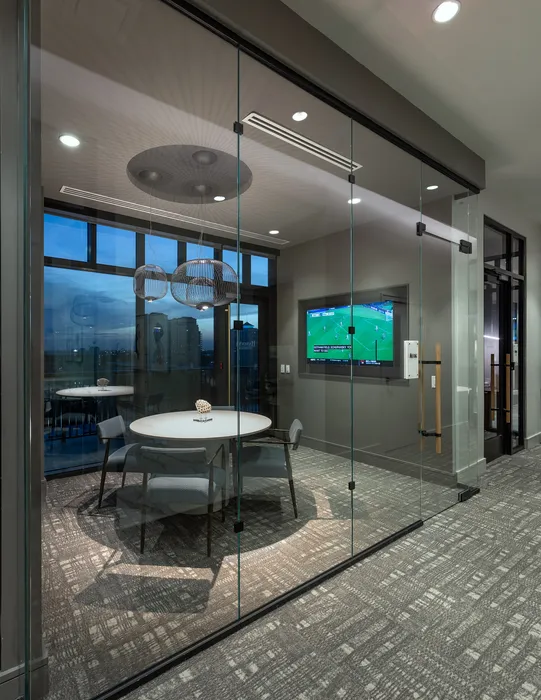 Modern conference room with sleek glass walls, stylish pendant lights, and a round table, creating an elegant and professional atmosphere.