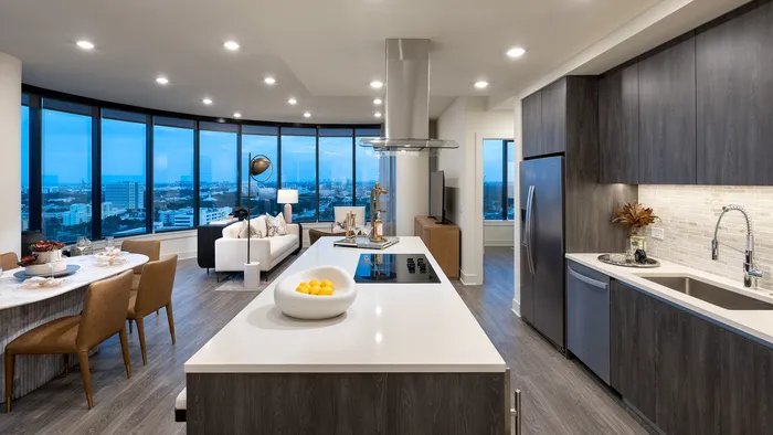 Luxurious modern apartment interior with open-concept layout, highlighting a sleek kitchen and expansive floor-to-ceiling windows offering stunning city views.