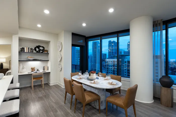 Sophisticated dining area with elegant table set for six, featuring chic cityscape views and stylish built-in shelving.