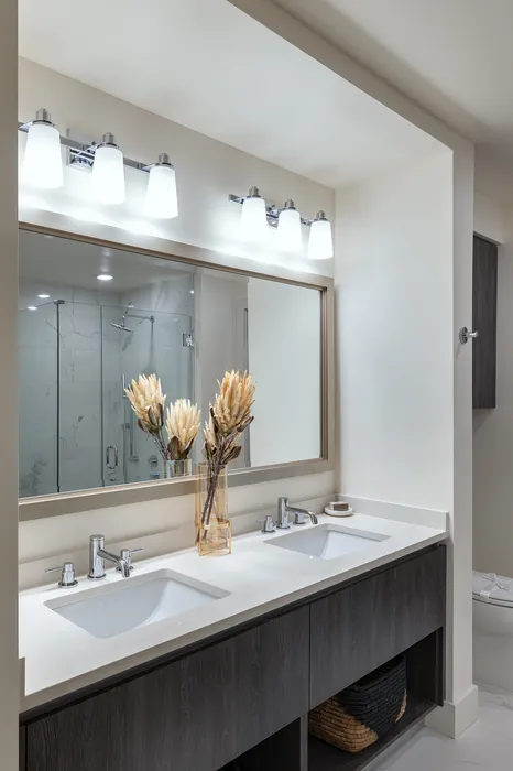 Elegant bathroom with dual sinks, modern lighting, and a stylish glass shower.