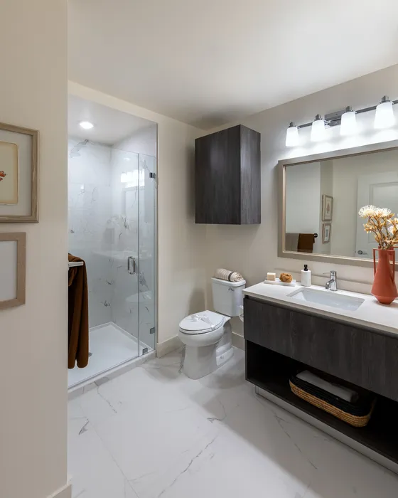 Elegant bathroom featuring a sleek modern vanity, glass-enclosed shower, and stylish lighting, perfect for a luxurious living experience.