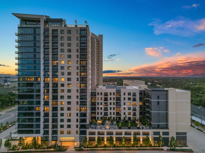 Modern high-rise apartment building with illuminated windows at sunset, offering stunning views and state-of-the-art amenities.