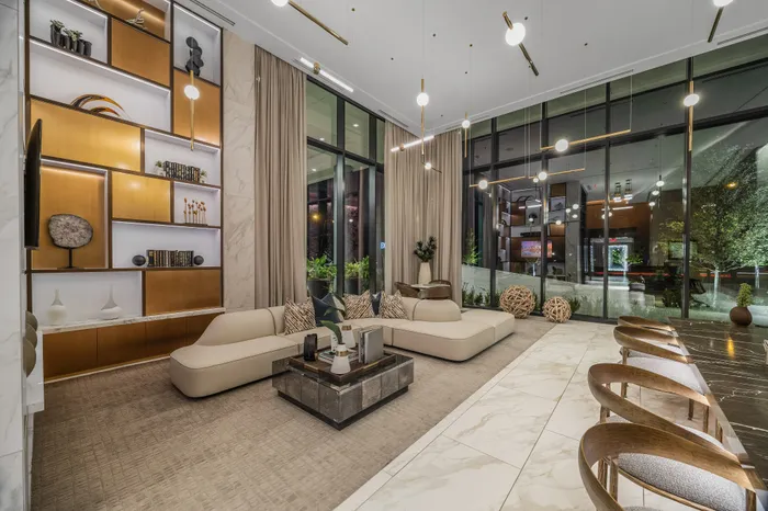Luxurious modern living room with stylish shelving, elegant lighting, plush seating, and floor-to-ceiling windows showcasing lush greenery.