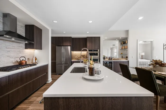 Modern kitchen with sleek dark wood cabinetry, stainless steel appliances, and a central island accented by stylish decor and elegant seating.