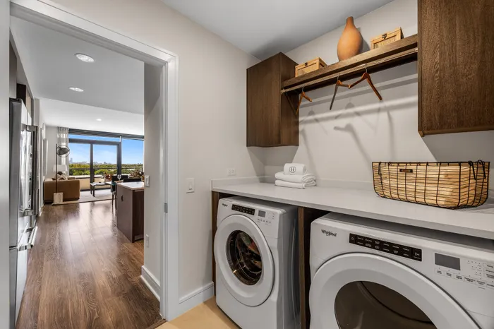 Contemporary apartment showcasing a sleek laundry area transitioning into a luxurious living space with city views.
