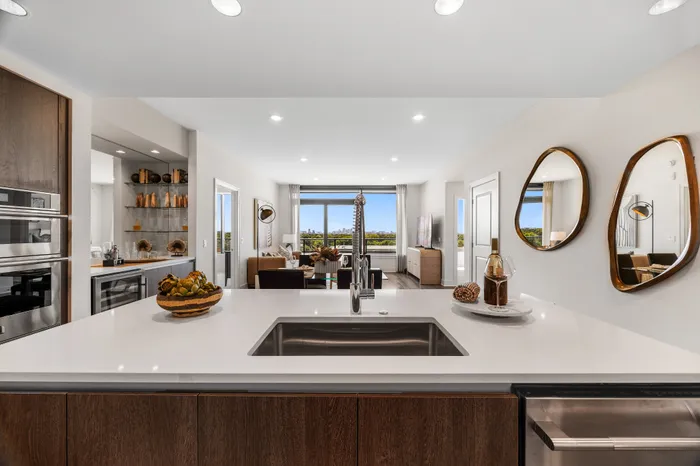 Modern open-plan living room with stylish kitchen island, elegant decor, and panoramic city views.