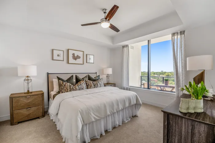 Inviting bedroom with elegant decor, featuring a cozy bed, stylish side tables with modern lamps, and a large window offering scenic views.