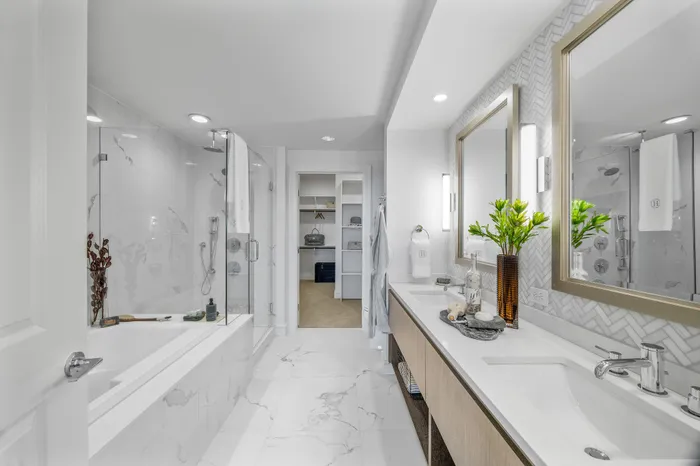 Elegant and modern bathroom showcasing marble finishes, a spacious tub, glass shower, and dual vanity with stylish decor.