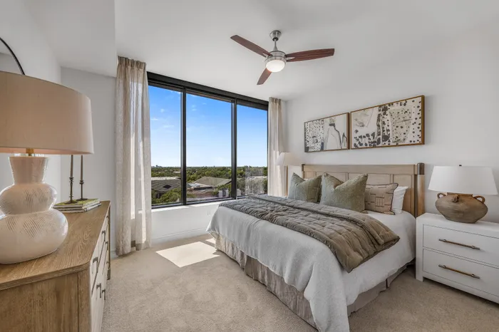 Bright and inviting bedroom with large windows offering a scenic view, featuring stylish decor and cozy bedding.
