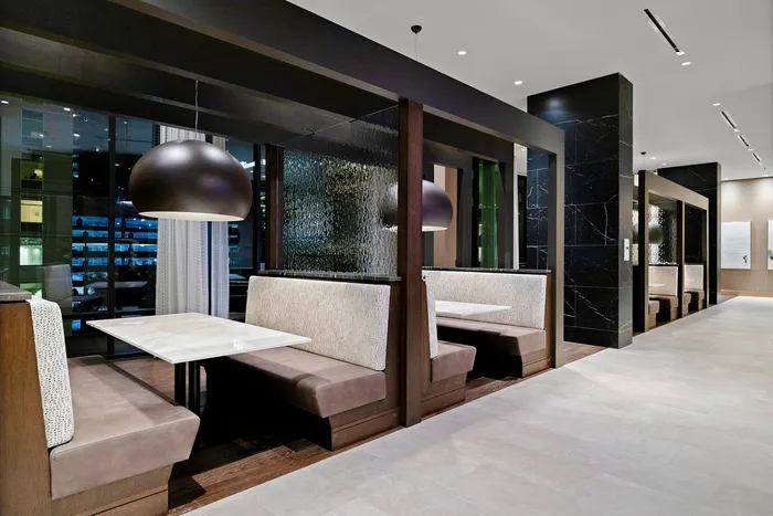 Elegant dining area with modern booths, chic lighting, and large windows offering a stunning city view.
