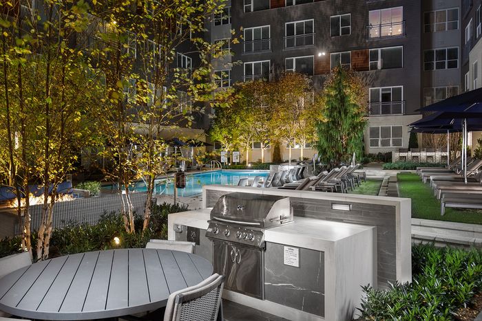 Luxurious outdoor courtyard featuring a gourmet BBQ area, stylish seating, and a sparkling swimming pool with lush greenery.